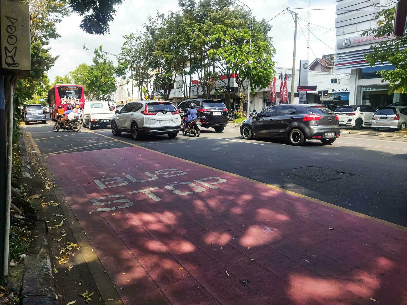 surakarta, indonesien - april 27, 2023. fordon trafik med några motorcyklar och bilar på väg med byggnader bakgrund i stor stad foto