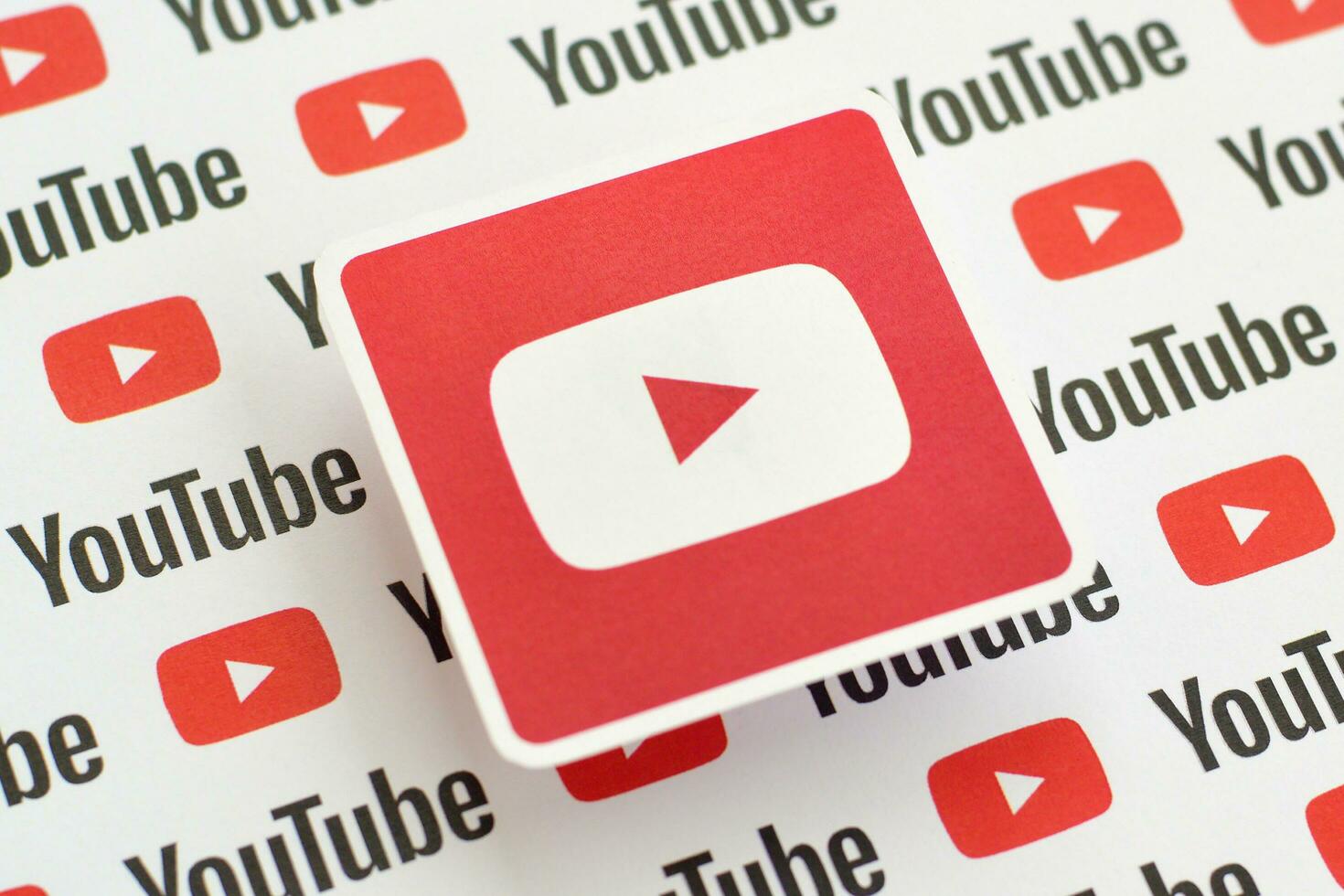 Youtube logotyp klistermärke på mönster tryckt på papper med små Youtube logotyper och inskriptioner. Youtube är Google dotterföretag och amerikan mest populär videodelning plattform foto