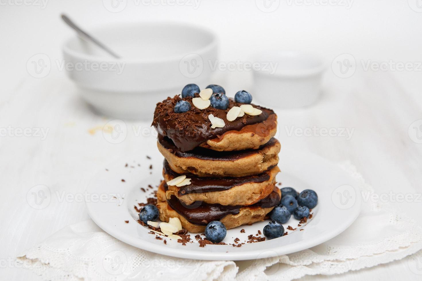 pannkakor med blåbär och chokladsås på vit tallrik och bord foto