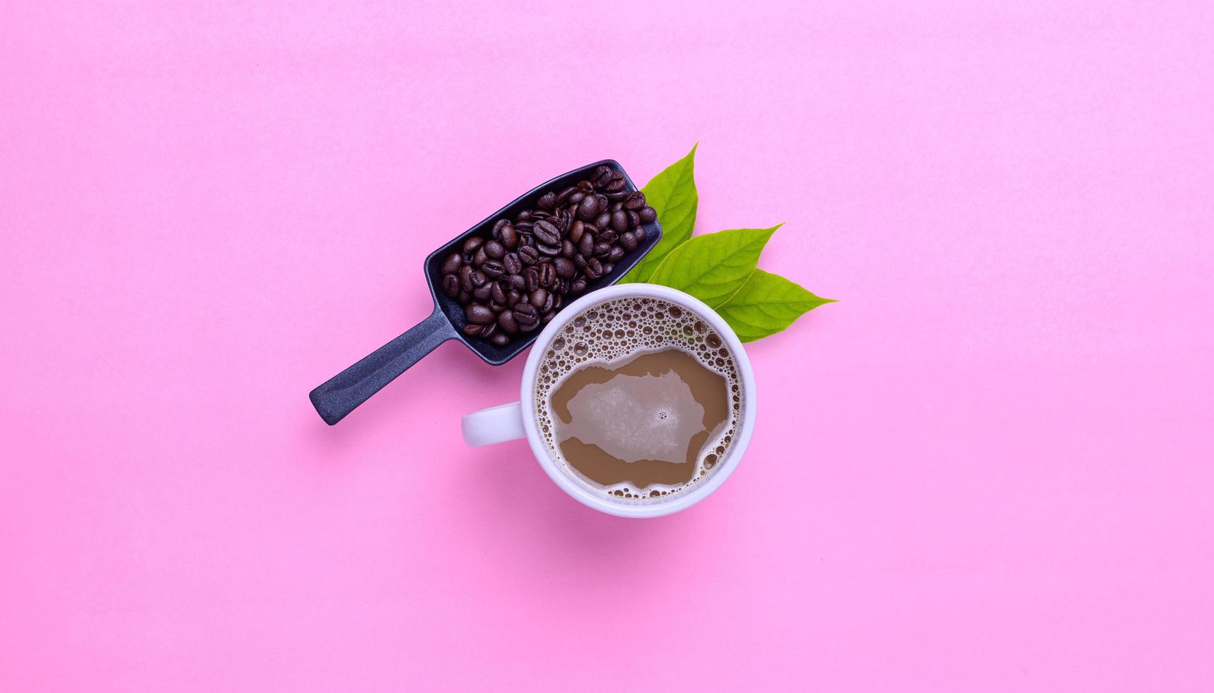 kaffemugg och kaffebönor på en rosa bakgrund foto