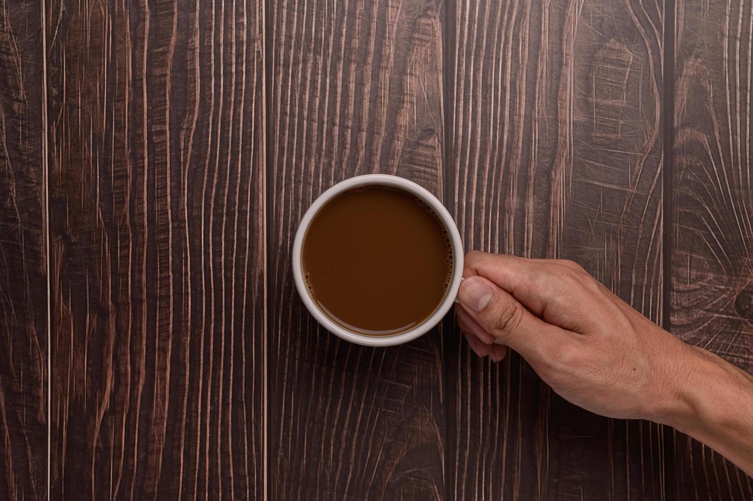 hand som håller en kaffemugg på en träbakgrund foto