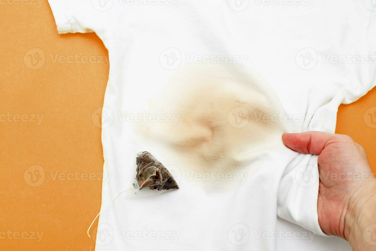 kvinna hand innehav vit kläder med en smutsig te färga med en te väska Nästa till den foto