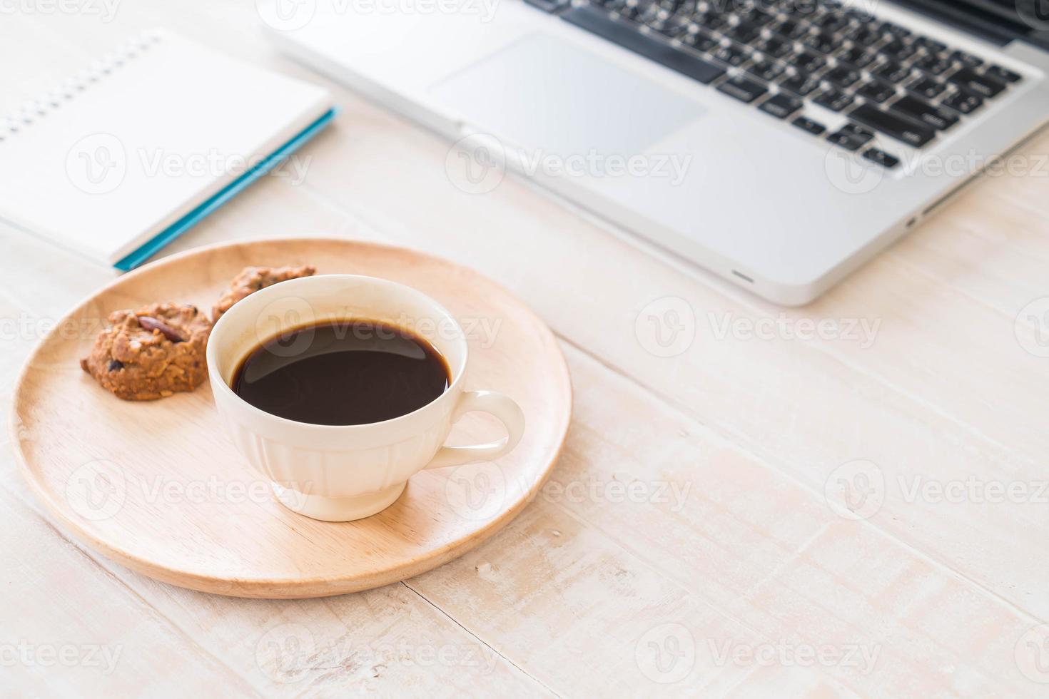 svart kaffe och kakor med bärbar dator och anteckningsbok på bordet foto