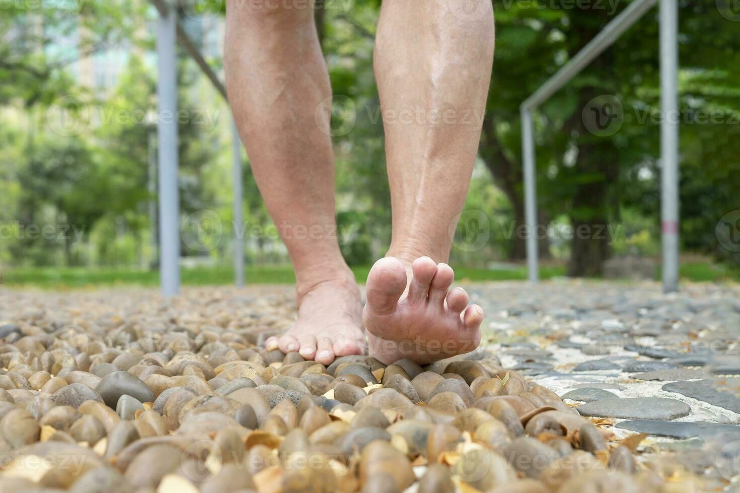 barfota gammal man stepping på stenar, fot zonterapi på de park.koncept av fot massage för öka blod cirkulation i äldre, lättnad för trött och öm fötter foto