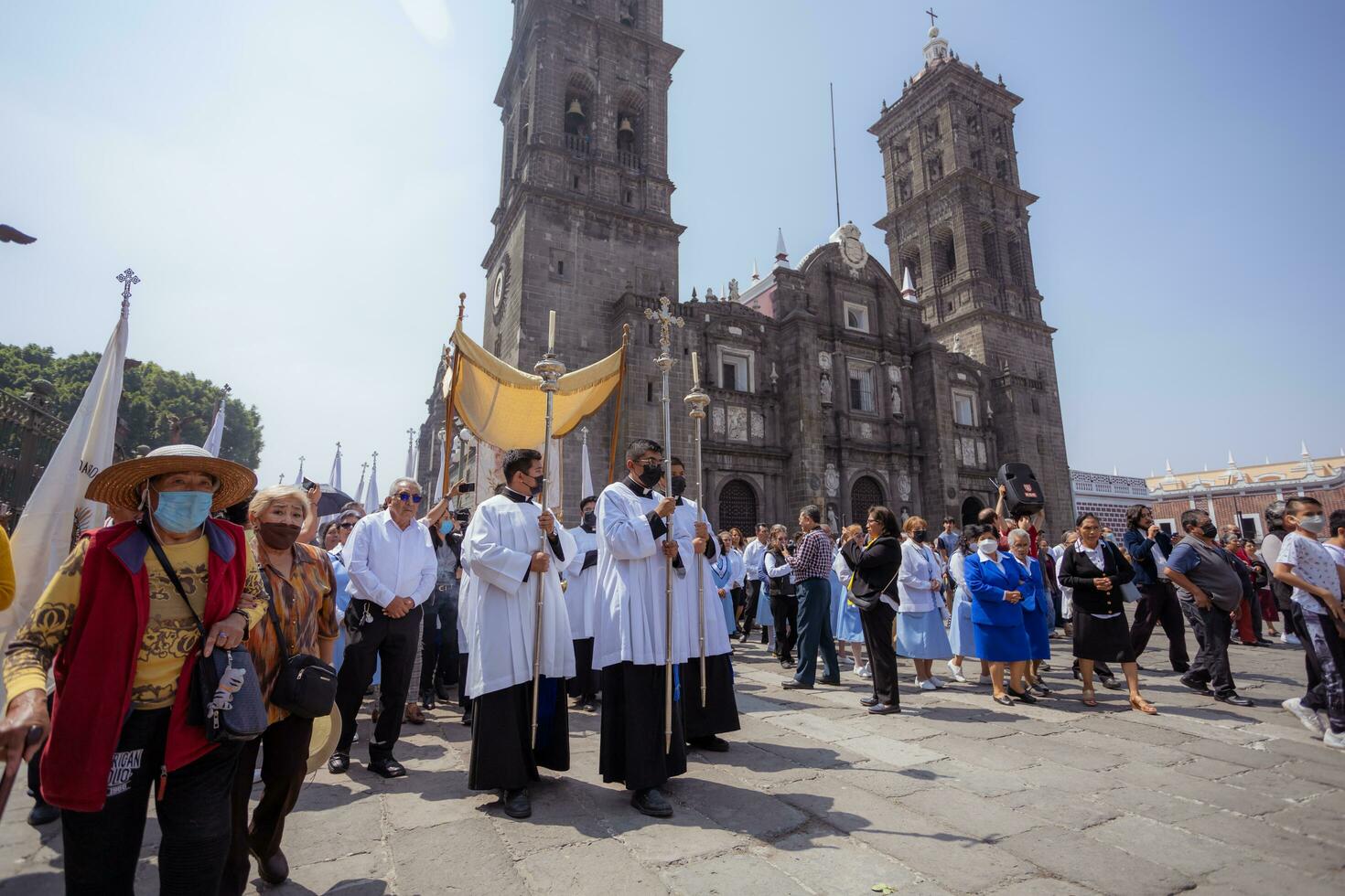 puebla, mexico 2023 - präster och medlemmar av de katolik kyrka bära ut en procession i främre av de katedral av puebla. dyrkan av katolik kristen symboler foto