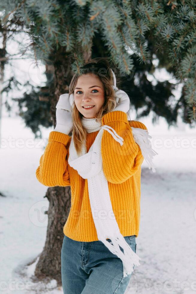 tonåring blond i en gul Tröja utanför i vinter. en Tonårs flicka på en promenad i vinter- kläder i en snöig skog foto