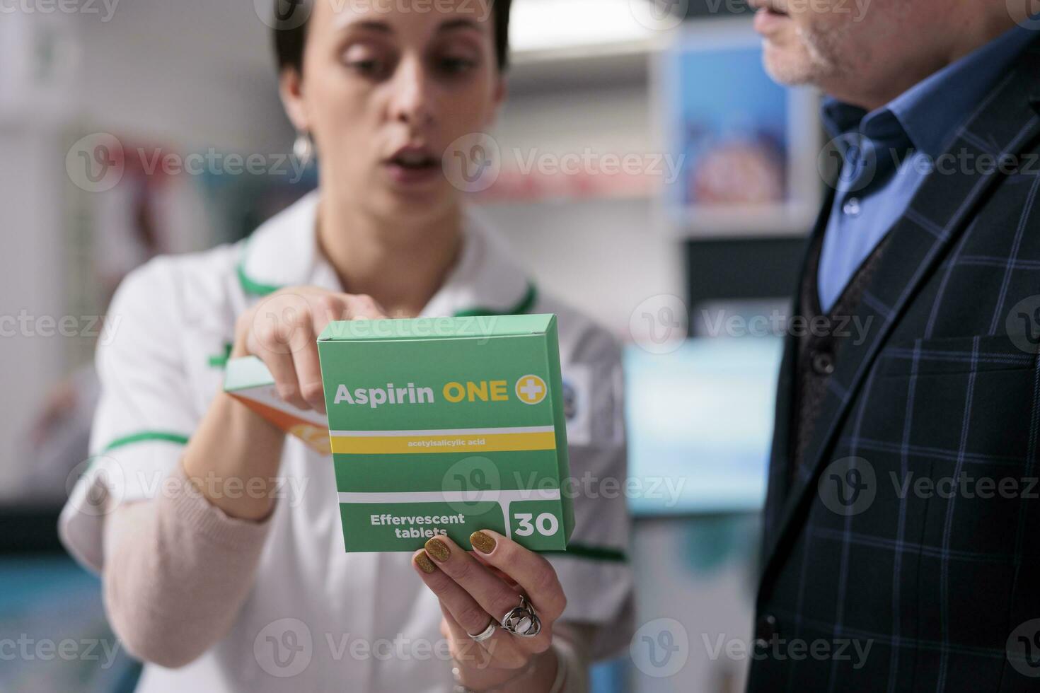 farmaceutisk konsult innehav smärtstillande paket och förklara aspirin dosering instruktion till kund i apotek. apotek anställd rådgivning man piller för inflammation behandling foto