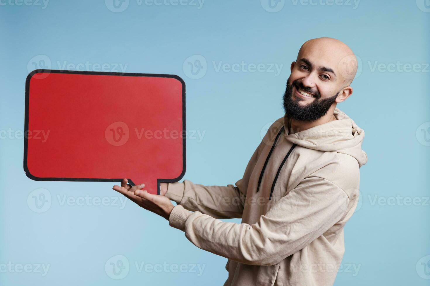 arab man innehav tom röd Tal ram produkt marknadsföring falsk upp och ser på kamera. leende sorglös person som visar tömma meddelande ram för reklam studio porträtt foto