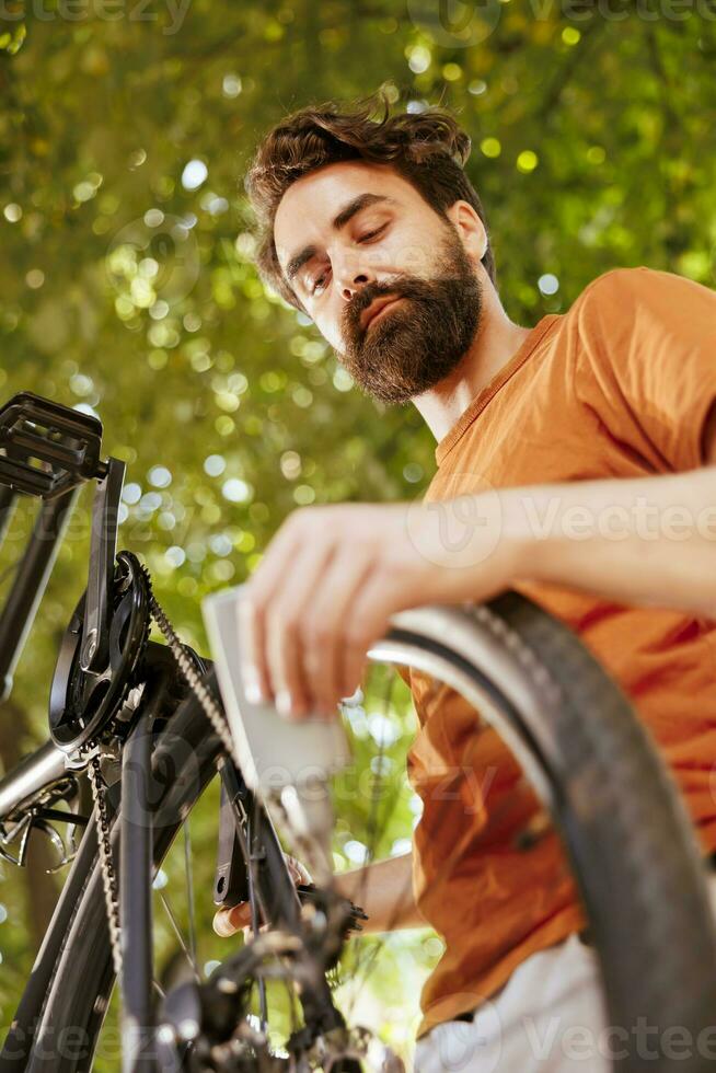 detaljerad skott av modern cykel kedja varelse noggrant smord med fett för säker utomhus- fritid. de bild visar Cyklar skiva broms ringa varelse smord förbi manlig cyklist som sommar underhåll foto
