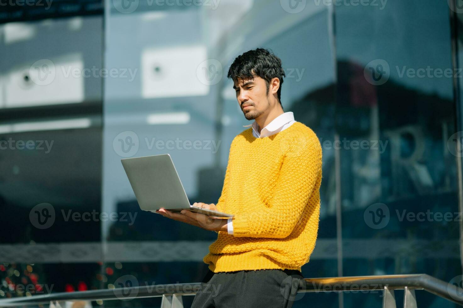 stilig ung affärsman använder sig av en digital läsplatta utanför ett kontor byggnad. foto