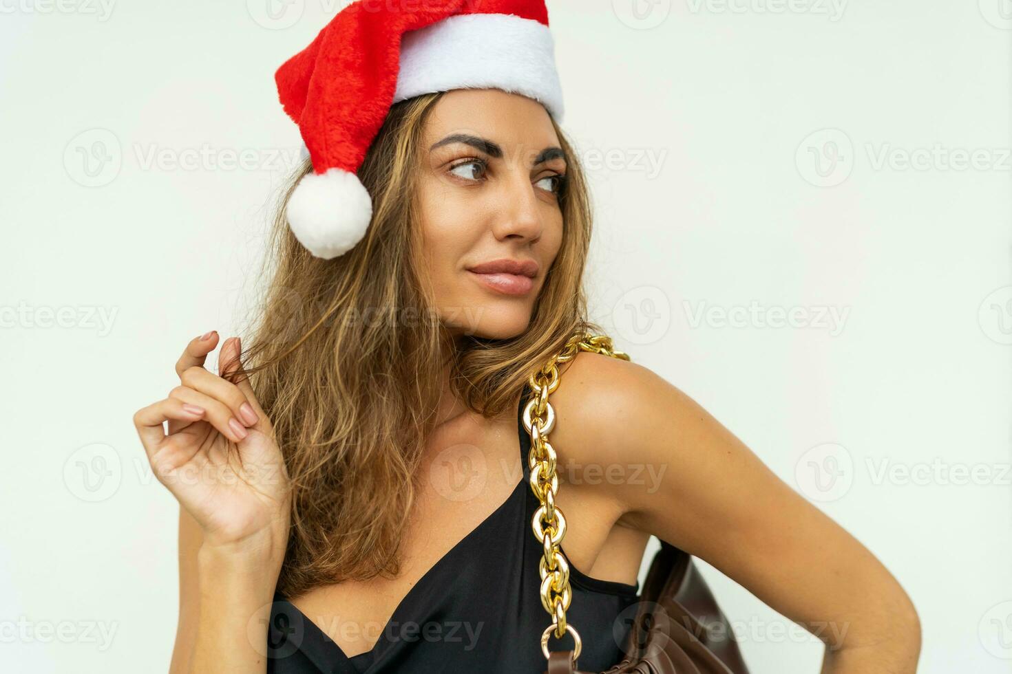 sexig ny år kvinna med Söt ansikte i svart klänning , perfekt solbränna kropp, ljus göra upp i röd jul santa claus Semester hatt Framställ på vit bakgrund . fest humör. foto