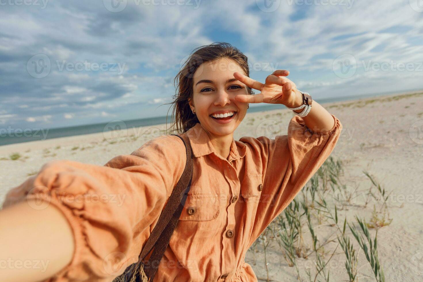 en kvinna i ett orange klänning och hatt på de strand foto