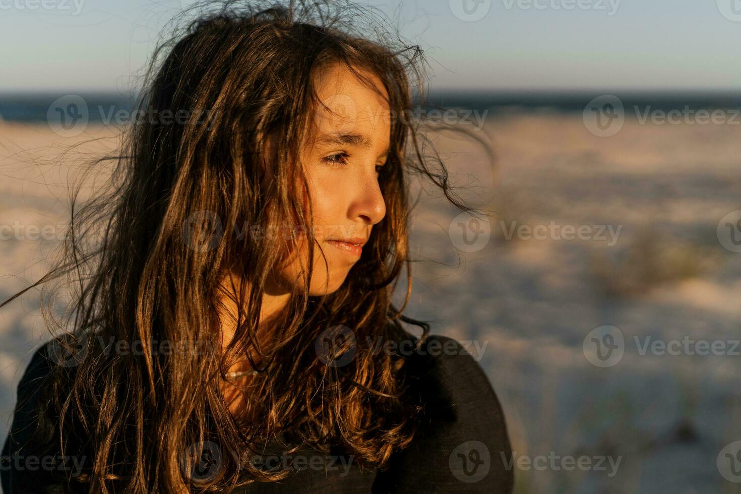 skön brunett barn flicka Framställ about de strand. solnedgång värma färger. foto