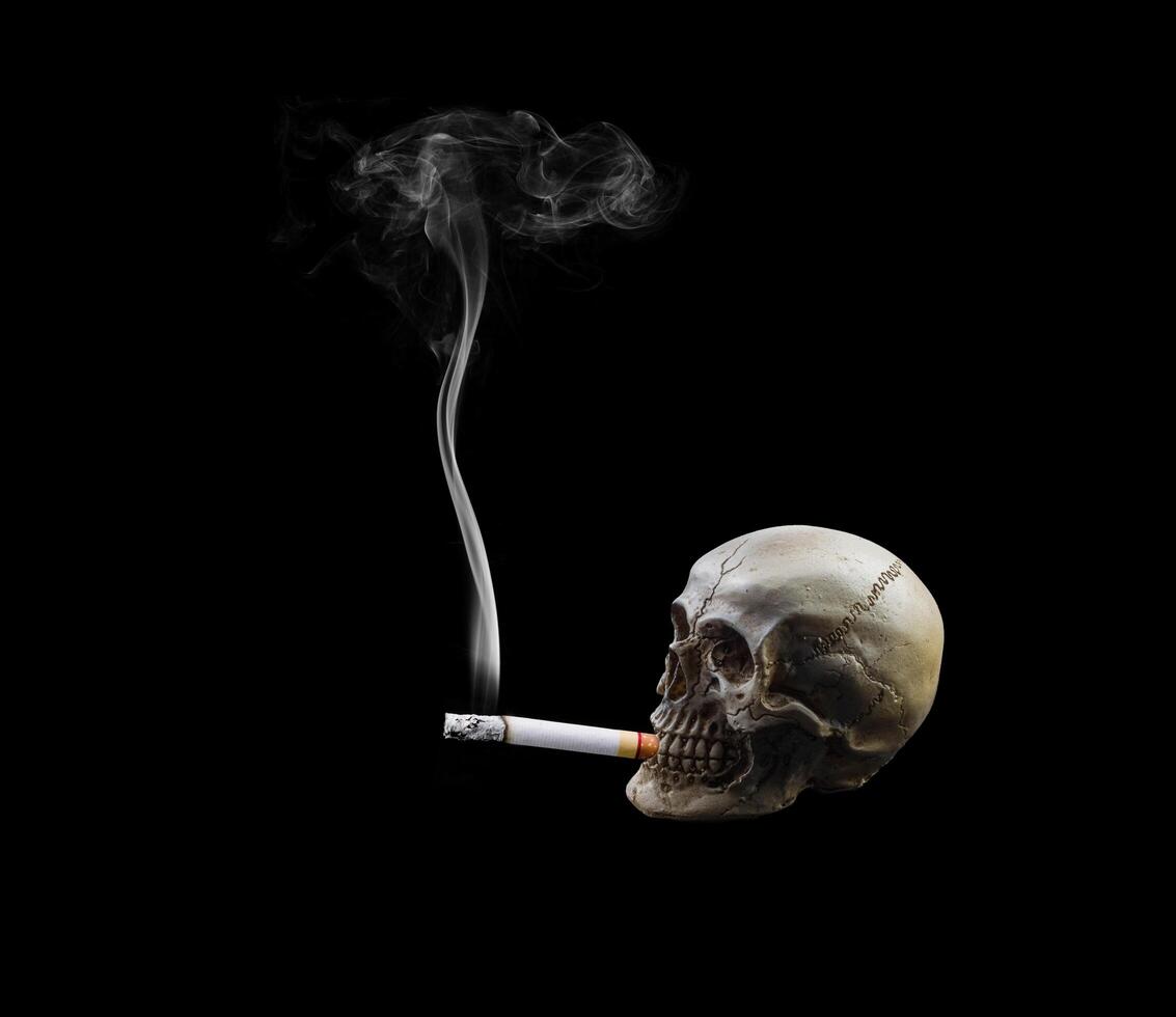 mänsklig skalle som röker en cigarett på svart bakgrund. foto