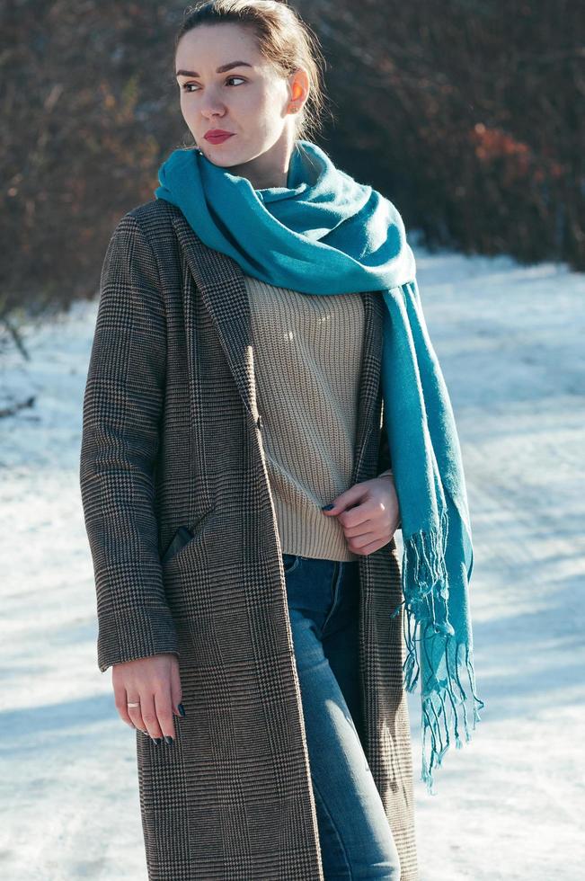 charmig tjej, blå halsduk och jeans, brun kappa, mode, vinterdag foto