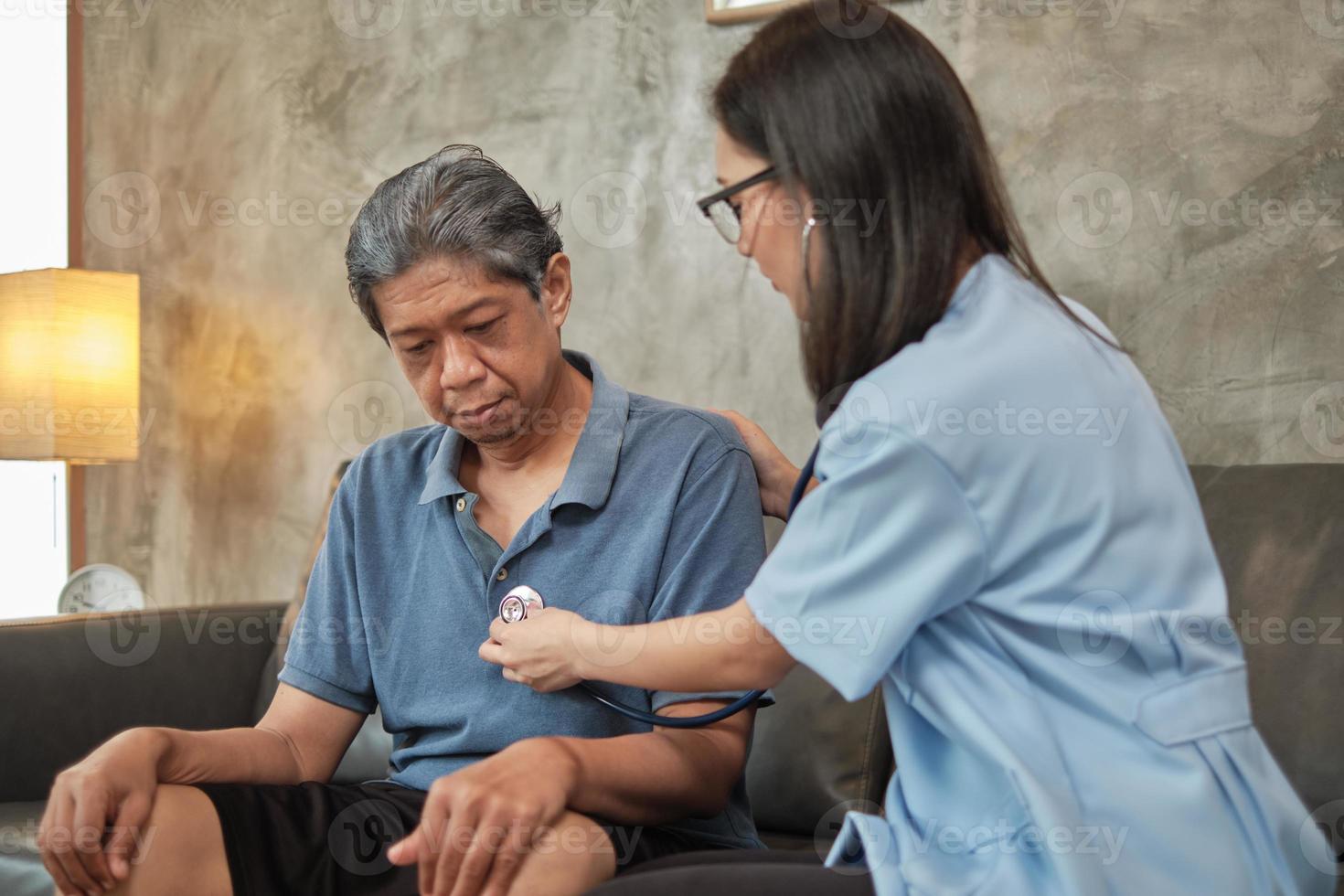 kvinnlig läkare som kontrollerar hälsan hos asiatisk äldre manlig patient hemma. foto