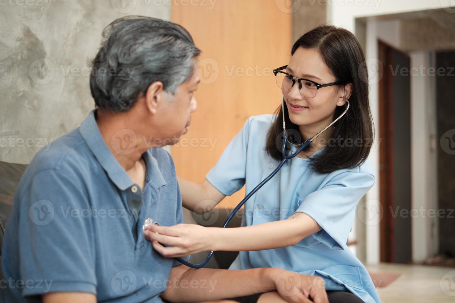 kvinnlig läkare som kontrollerar hälsan hos asiatisk äldre manlig patient hemma. foto