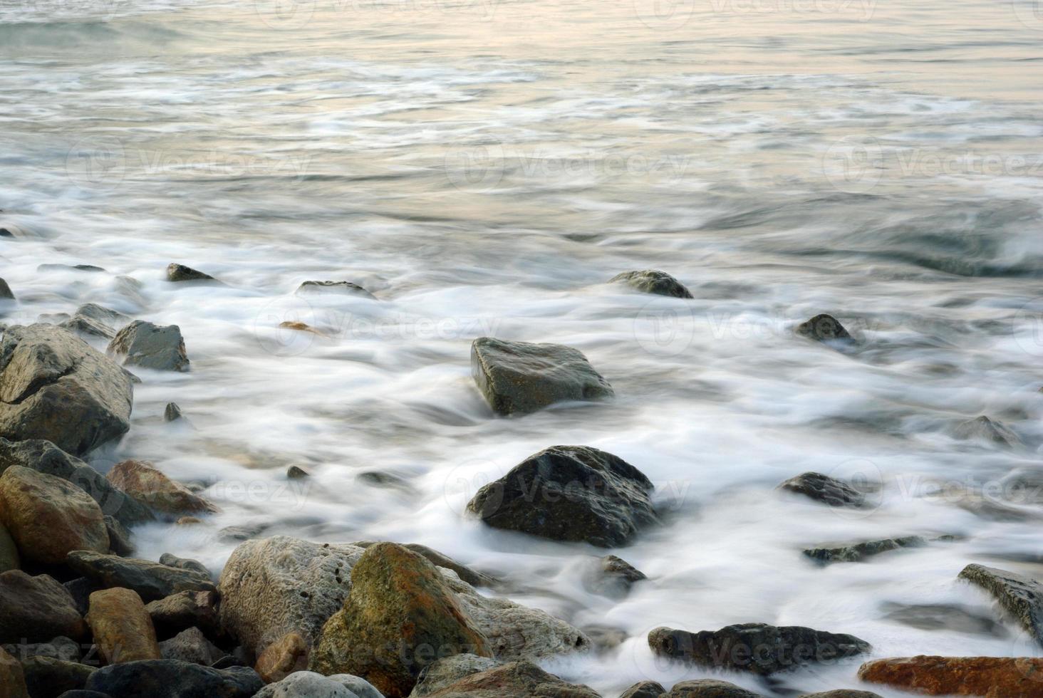 turbulens havsvatten och sten vid kusten foto