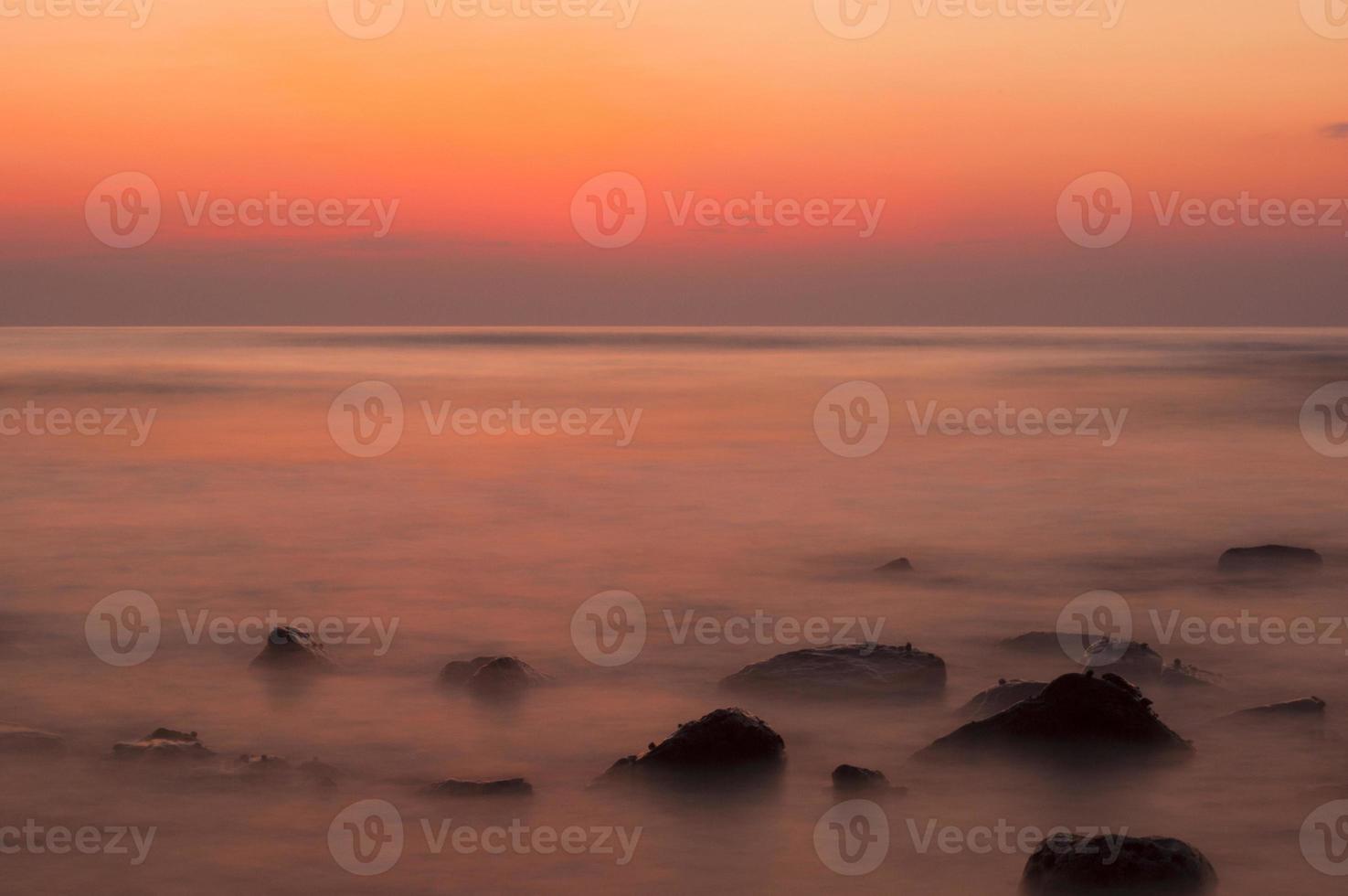 mjuka vågor på en stenig strand på kvällen foto