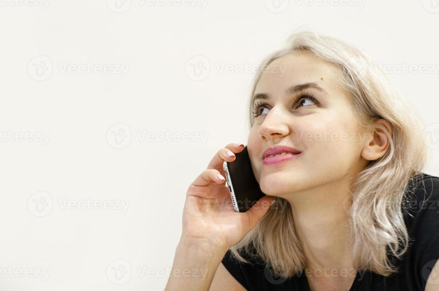 en ung flicka med blont hår kommunicerar i telefon. foto