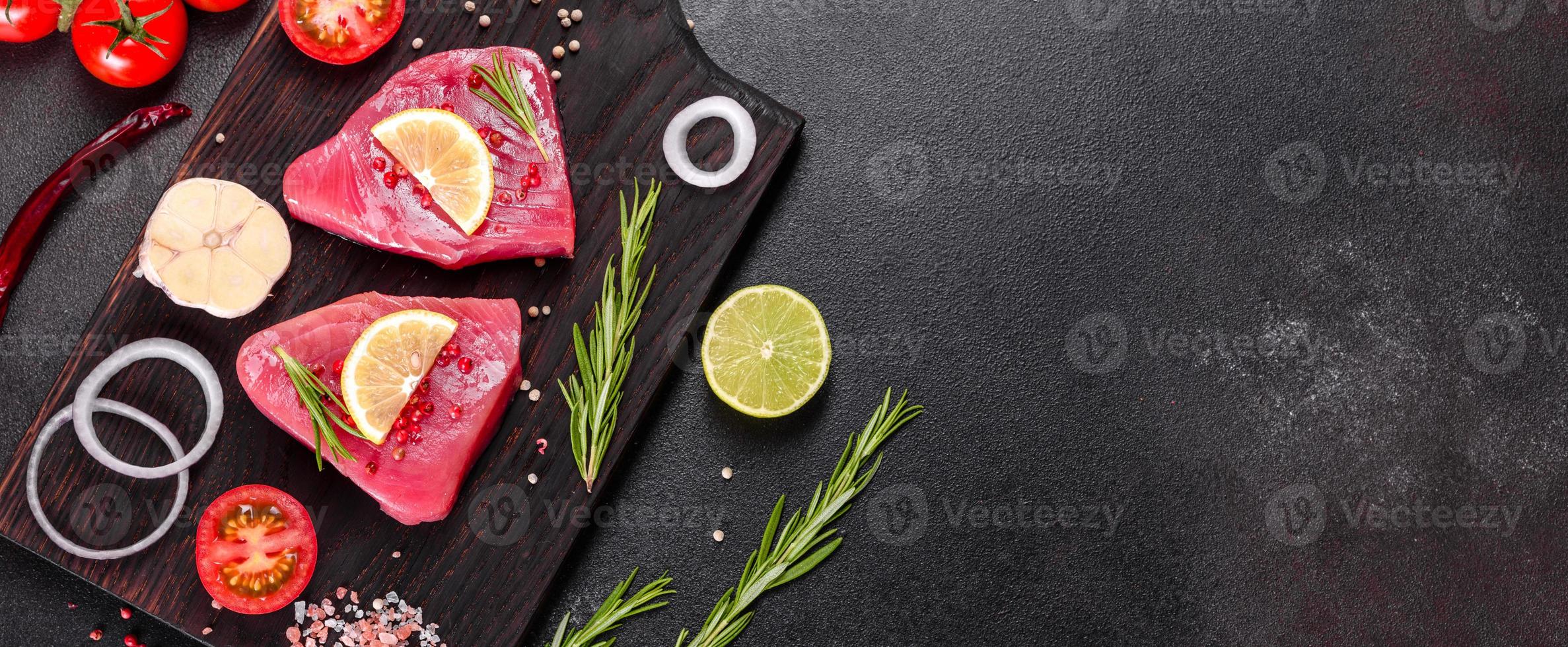 färsk tonfiskfilé med kryddor och örter på en svart bakgrund foto