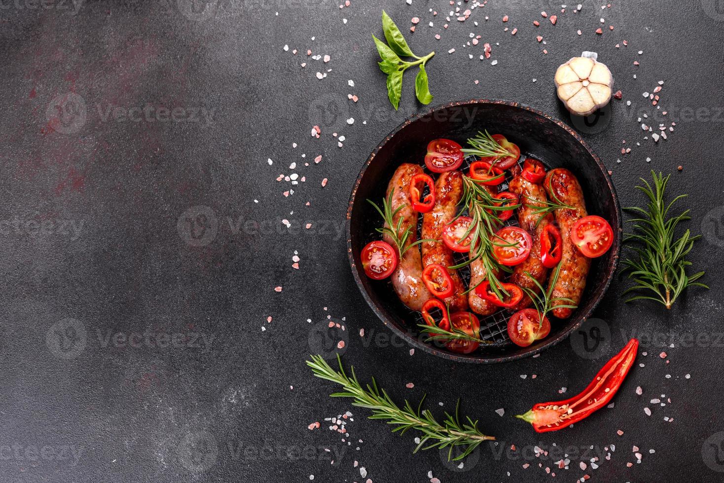 grillade korvar med grönsaker och kryddor på svart bakgrund foto