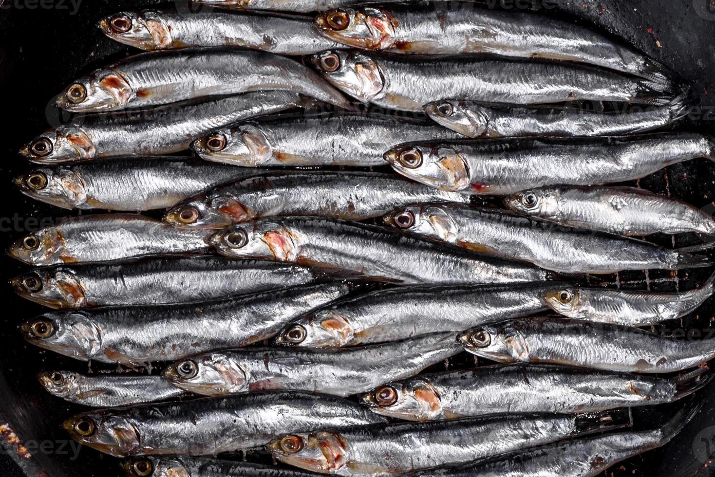 flera fisksaltade ansjovis på ett mörkt betongbord foto