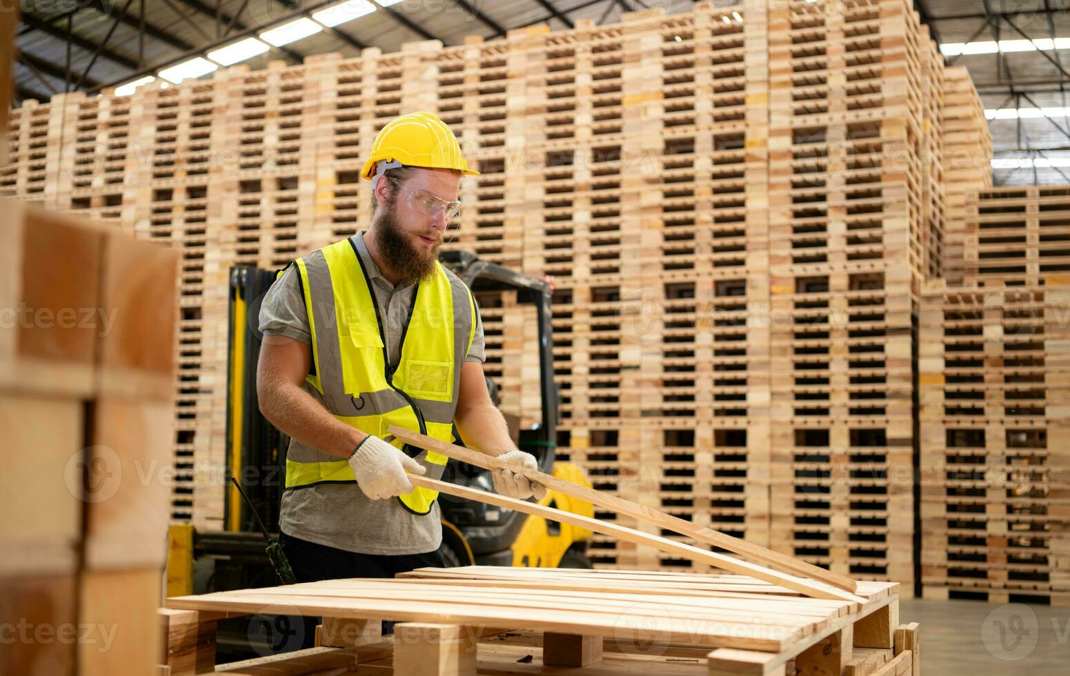 porträtt av ung manlig snickare arbetssätt i en träbearbetning fabrik, han är bär en säkerhet hjälm och glasögon, kontroll de trä- plankor kommande ut av de trä kvarn. foto