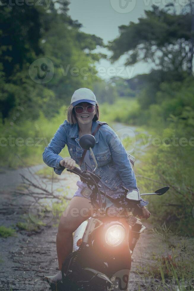 skön kvinna bär blå jeans jacka Sammanträde på enduro motorcykel mot färgrik naturlig bakgrund foto