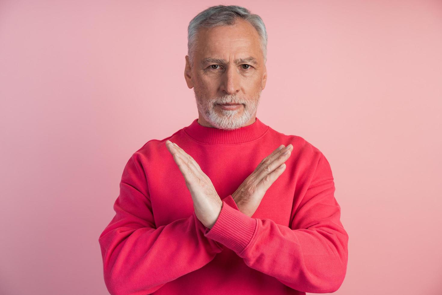 senior man gestikulerar på rosa bakgrund foto
