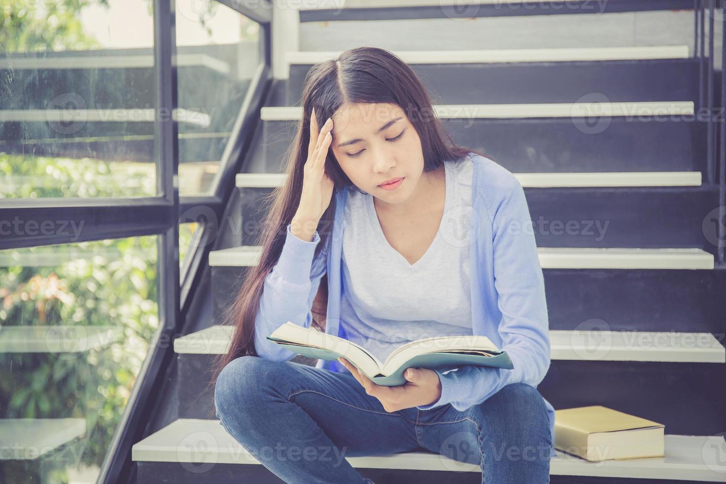 asiatisk kvinna läser bok studerar för tentor med trött. foto