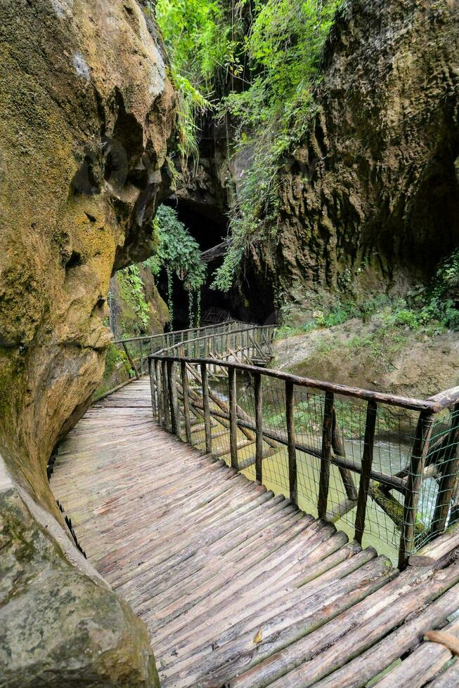 en trä- gångväg leder till en grotta i de bergen foto