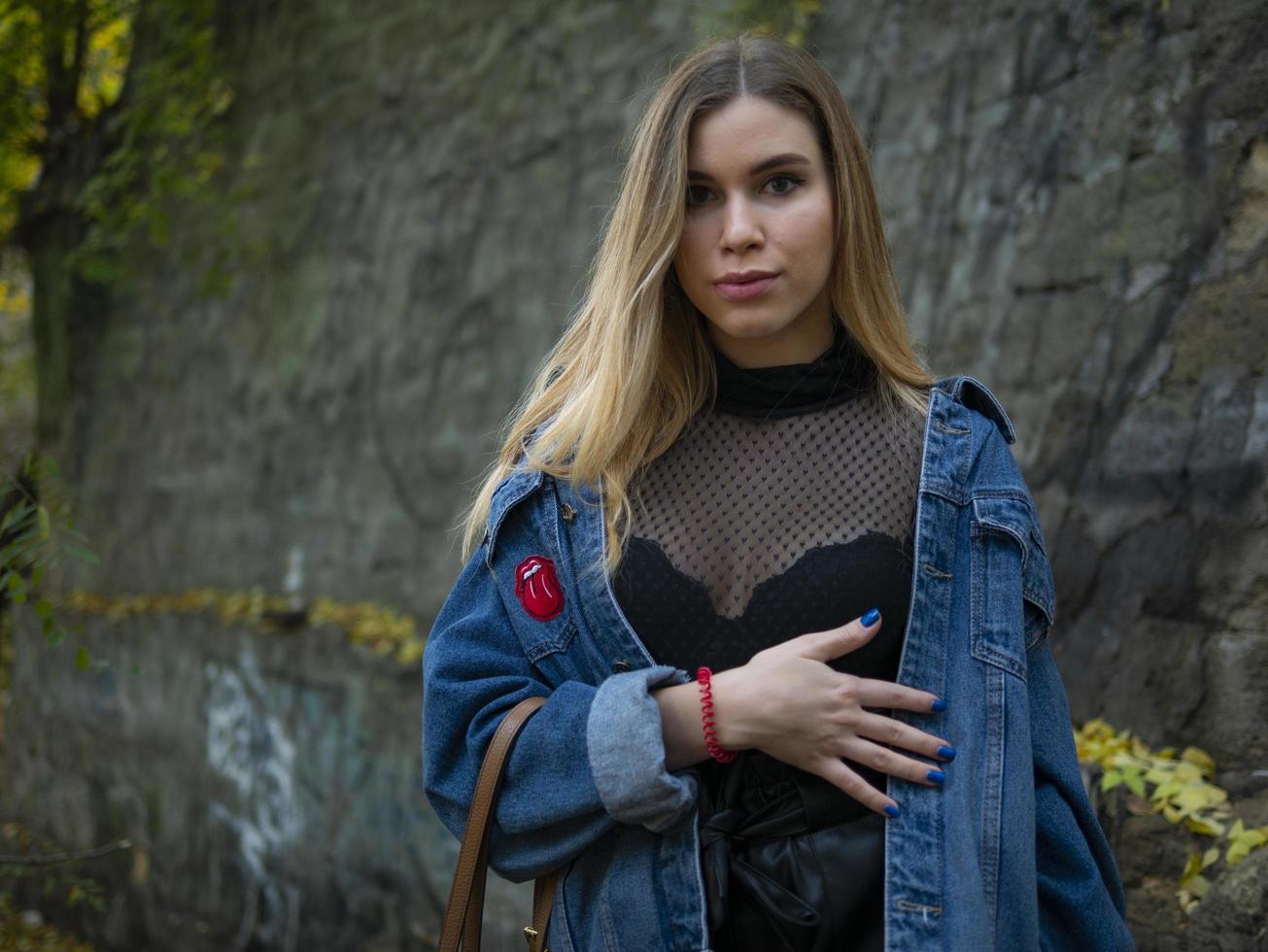 blond modellflicka i en jeansjacka står på gatan foto