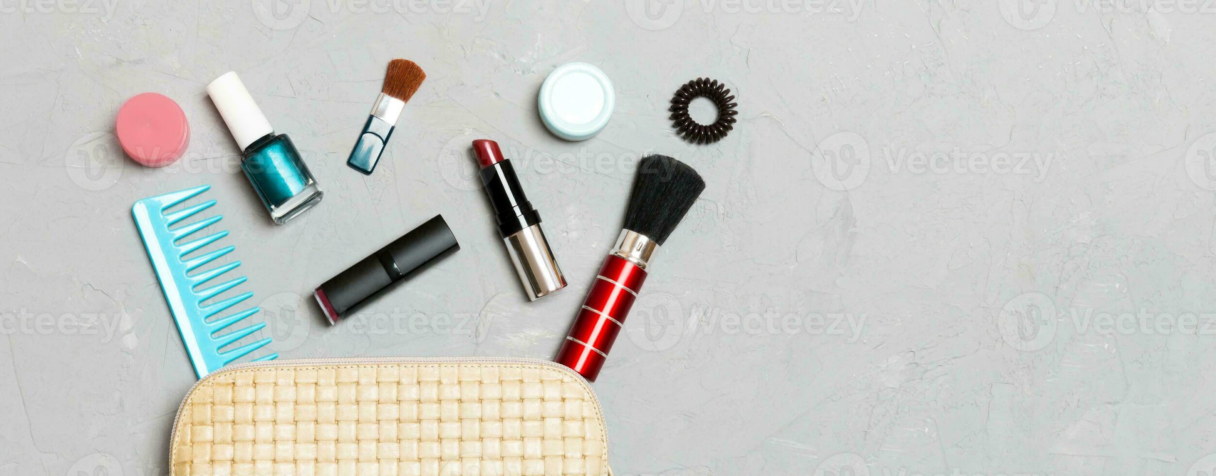 topp se av uppsättning av göra upp och hud vård Produkter spill ut av kosmetika väska på cement bakgrund. skönhet begrepp foto