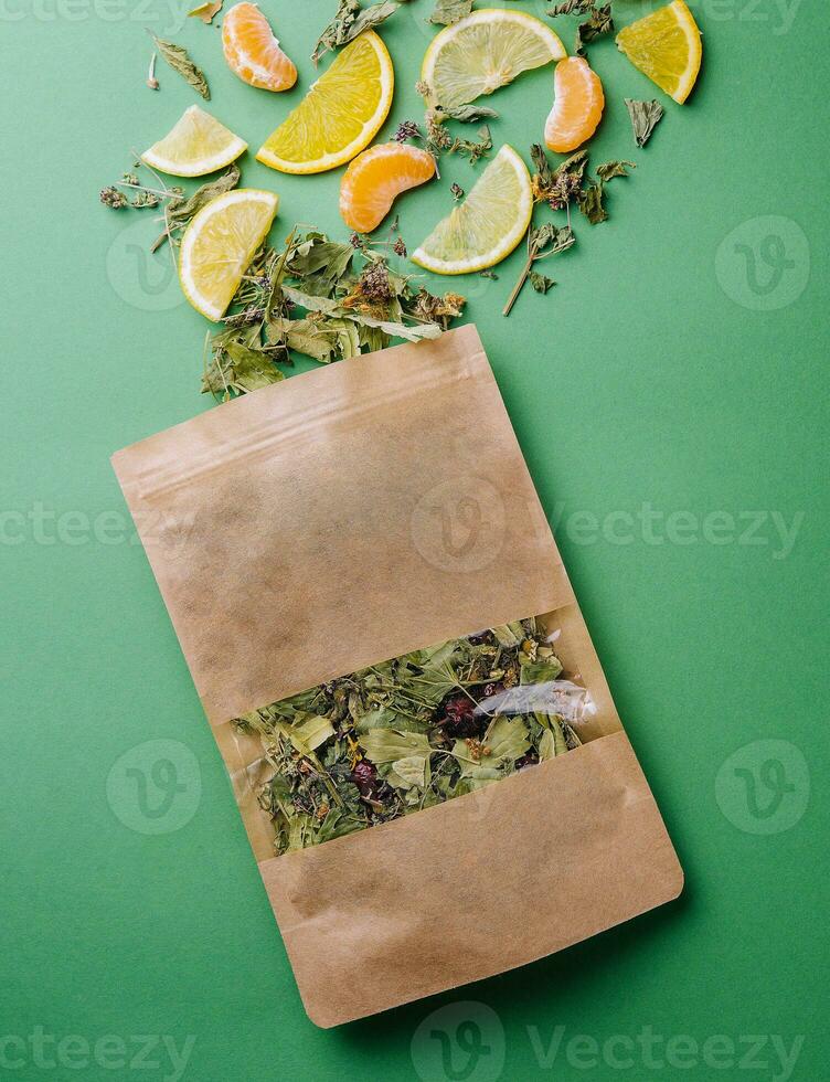 blad te spillts ut av en papper paket med orange och mandarin skivor på grön bakgrund foto