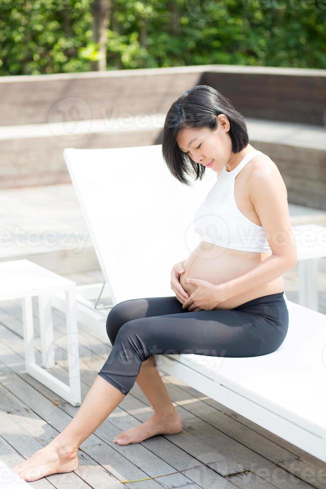 gravid asiatisk ung kvinna koppla av i parken. foto