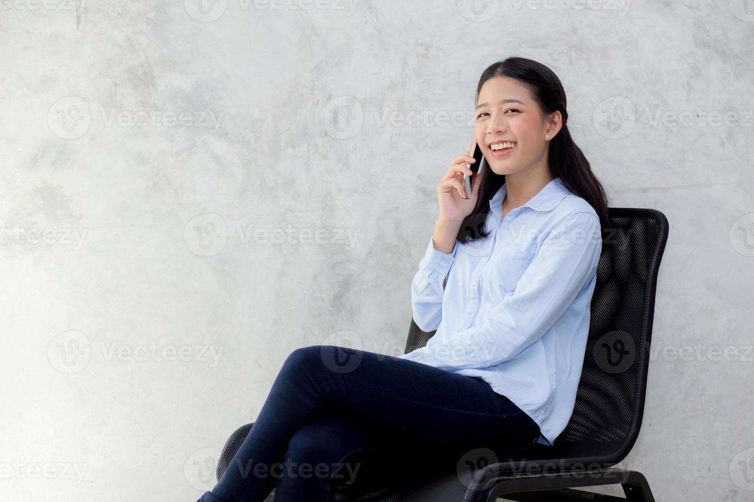 ung asiatisk kvinna pratar smart telefon och le. foto