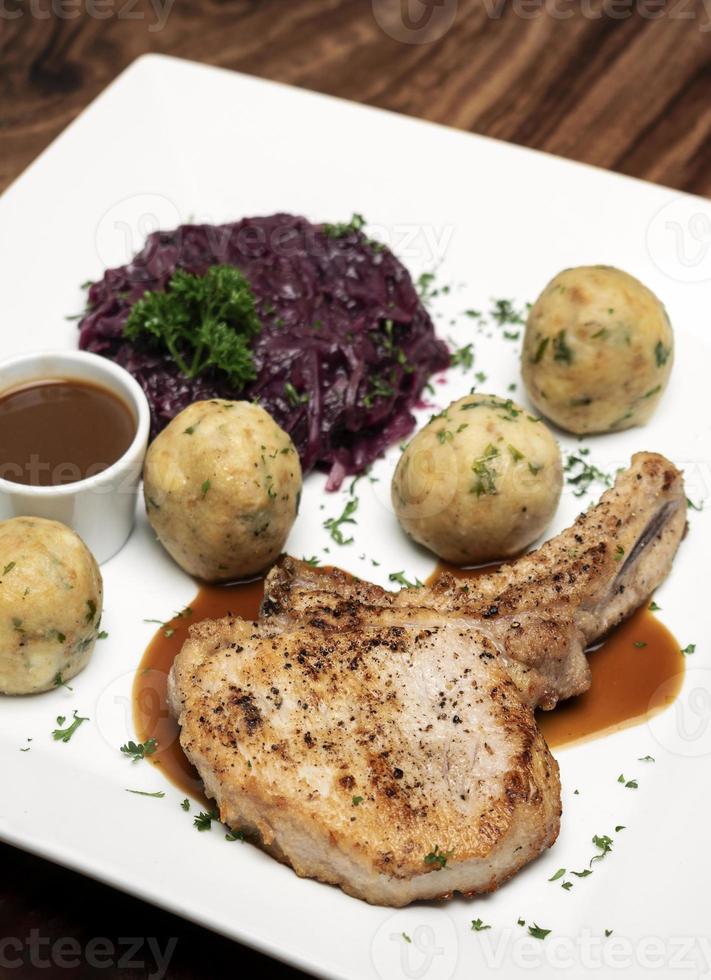 tysk grillad fläskkotlett med brödknölar och rödkåls traditionell måltid på träbord foto
