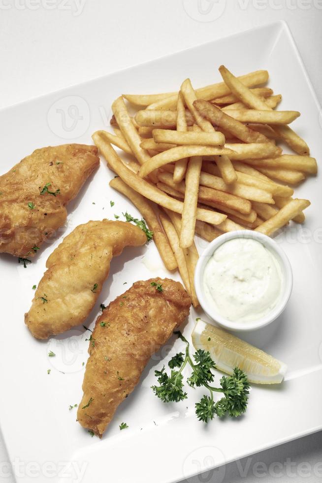 brittisk traditionell fish and chips -måltid på vit tallrik foto