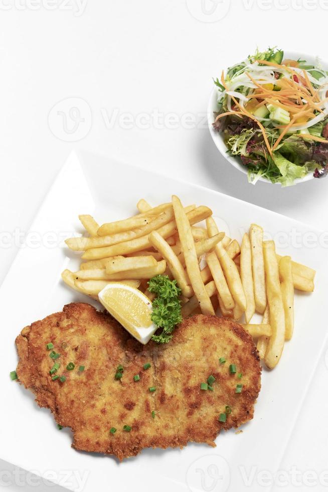 tyskbrödad fläskschnitzel med pommes frites på vit studiobakgrund foto