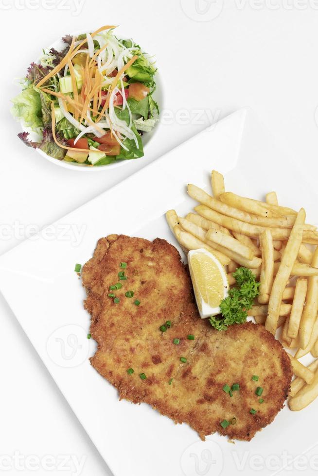 tyskbrödad fläskschnitzel med pommes frites på vit studiobakgrund foto