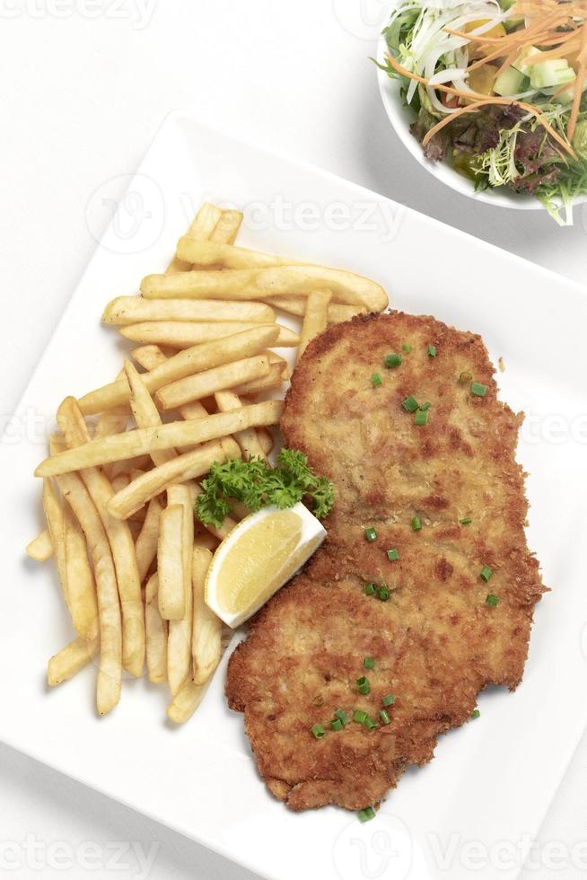 tyskbrödad fläskschnitzel med pommes frites på vit studiobakgrund foto