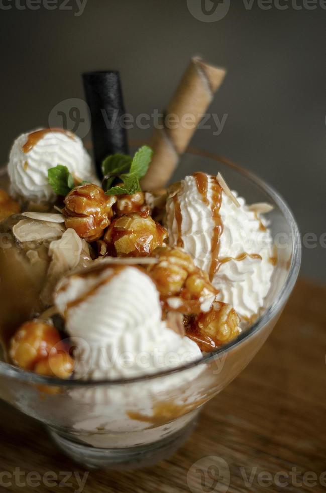 karamell- och mandelglass med karamelliserad popcorn -dessert i glasskål foto