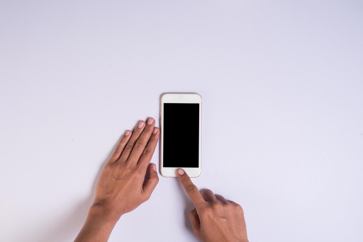 ovanifrån hand som håller mobiltelefon på vit bakgrund. foto