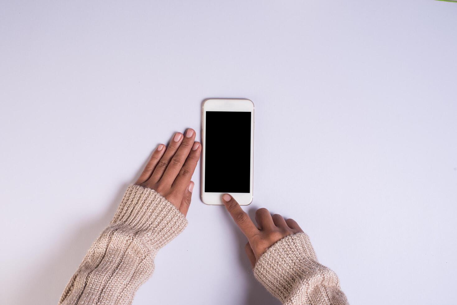 ovanifrån hand som håller mobiltelefon på vit bakgrund. foto