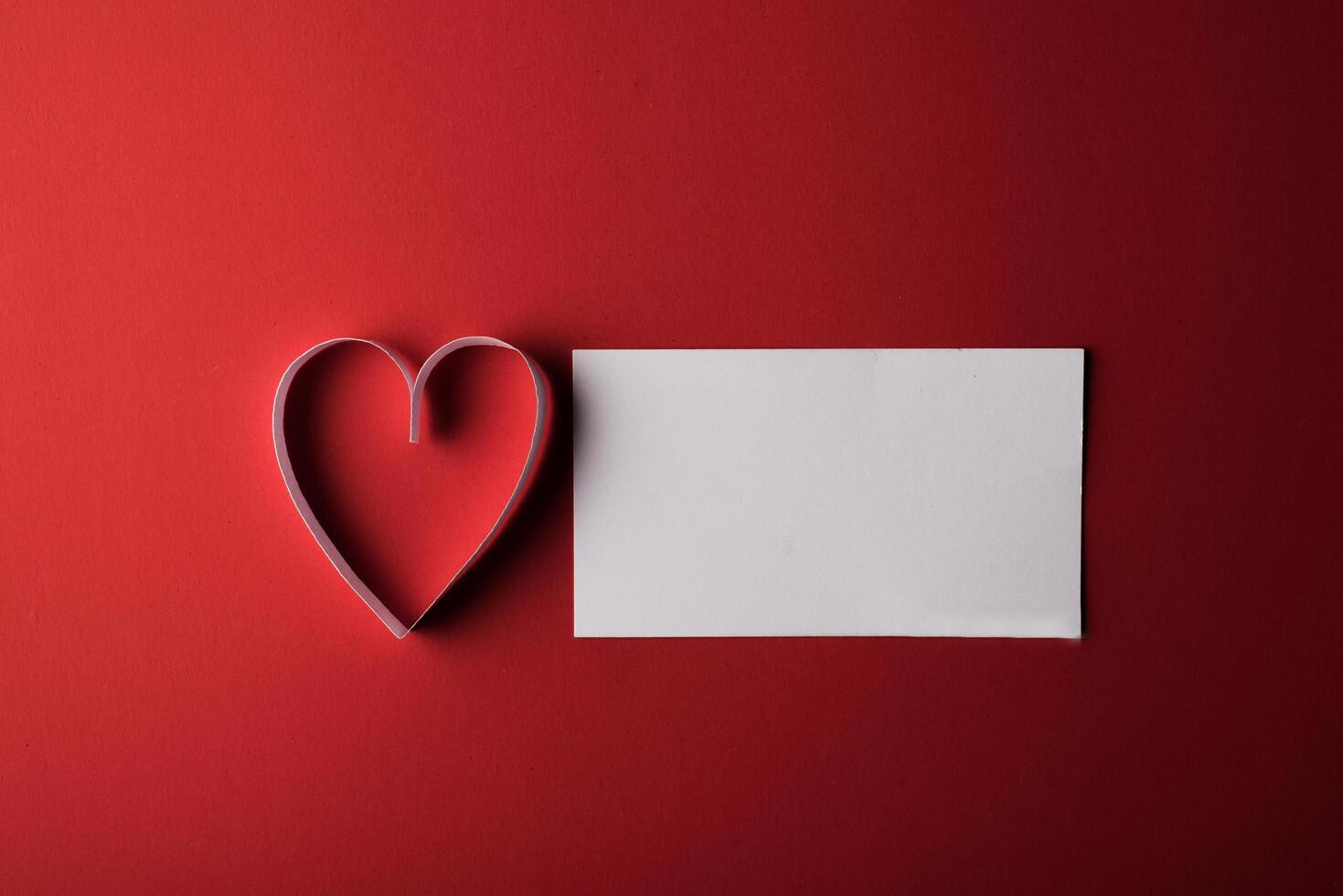 rött hjärtapapper och tomt med anteckningskort på röd bakgrund. foto