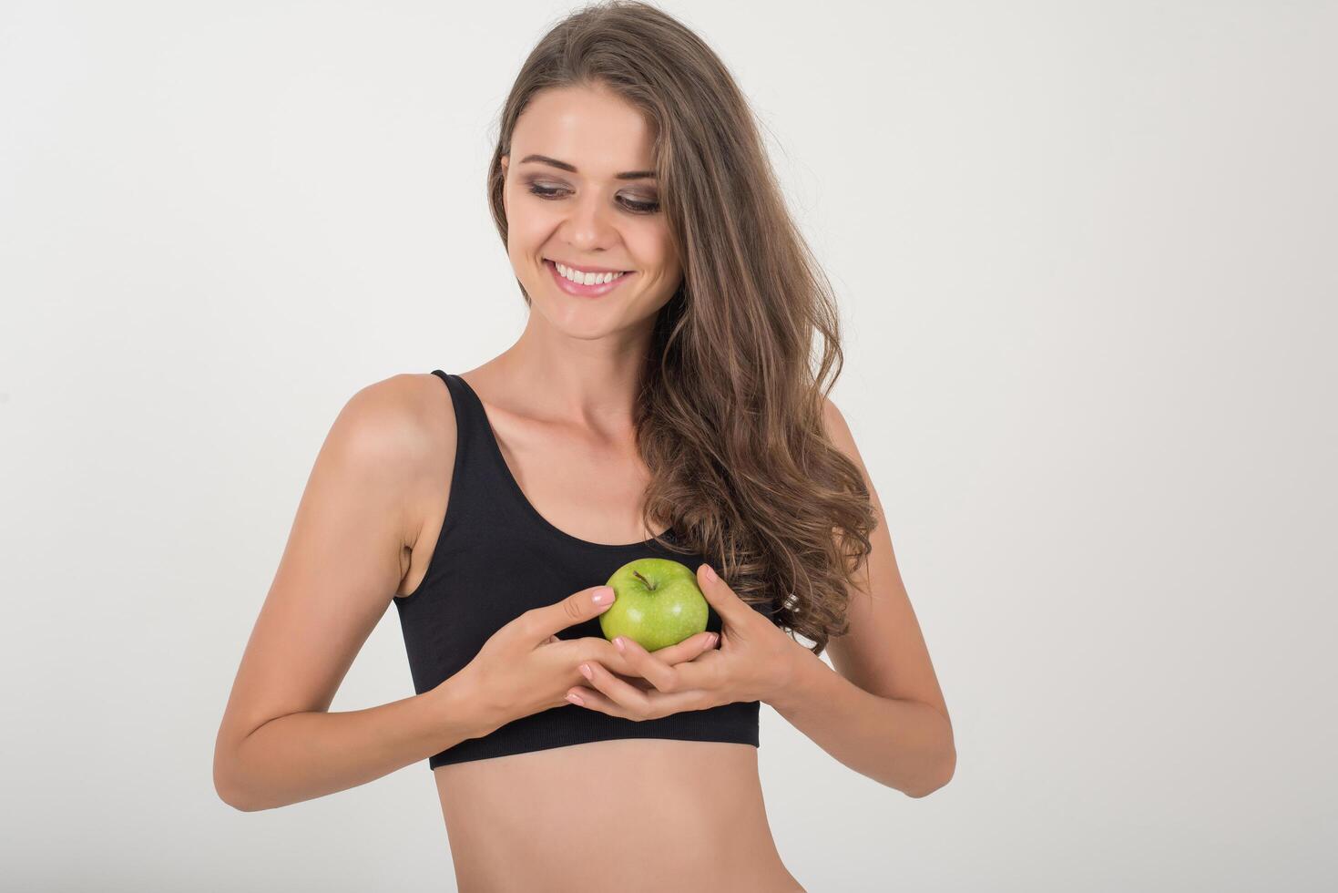 skönhetskvinna som håller grönt äpple medan det är isolerat på vitt. foto