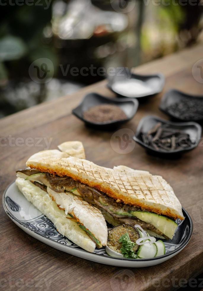 vegansk rostad grönsaksrökt panini -smörgås i rustik trädgårdsdukning utomhus på sicilien foto