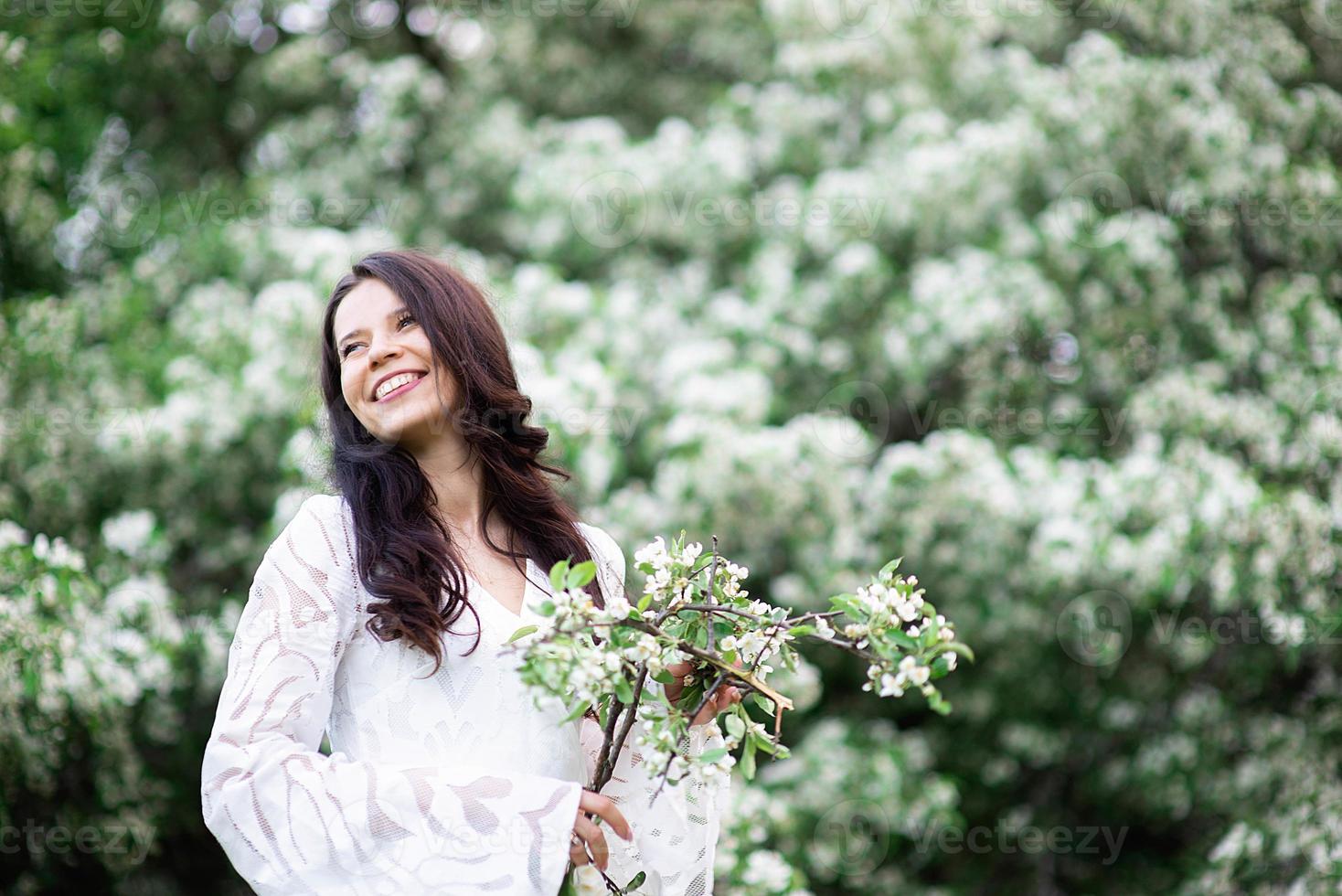 porträtt av en vacker ung kvinna i parken i blommande grenar foto