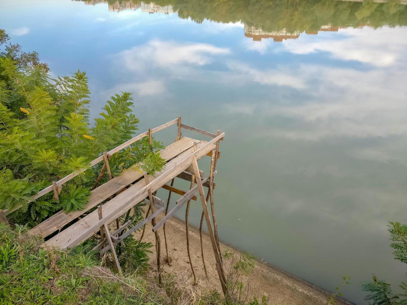 den höga bron av tallbrädor på flodens strand för fiske foto